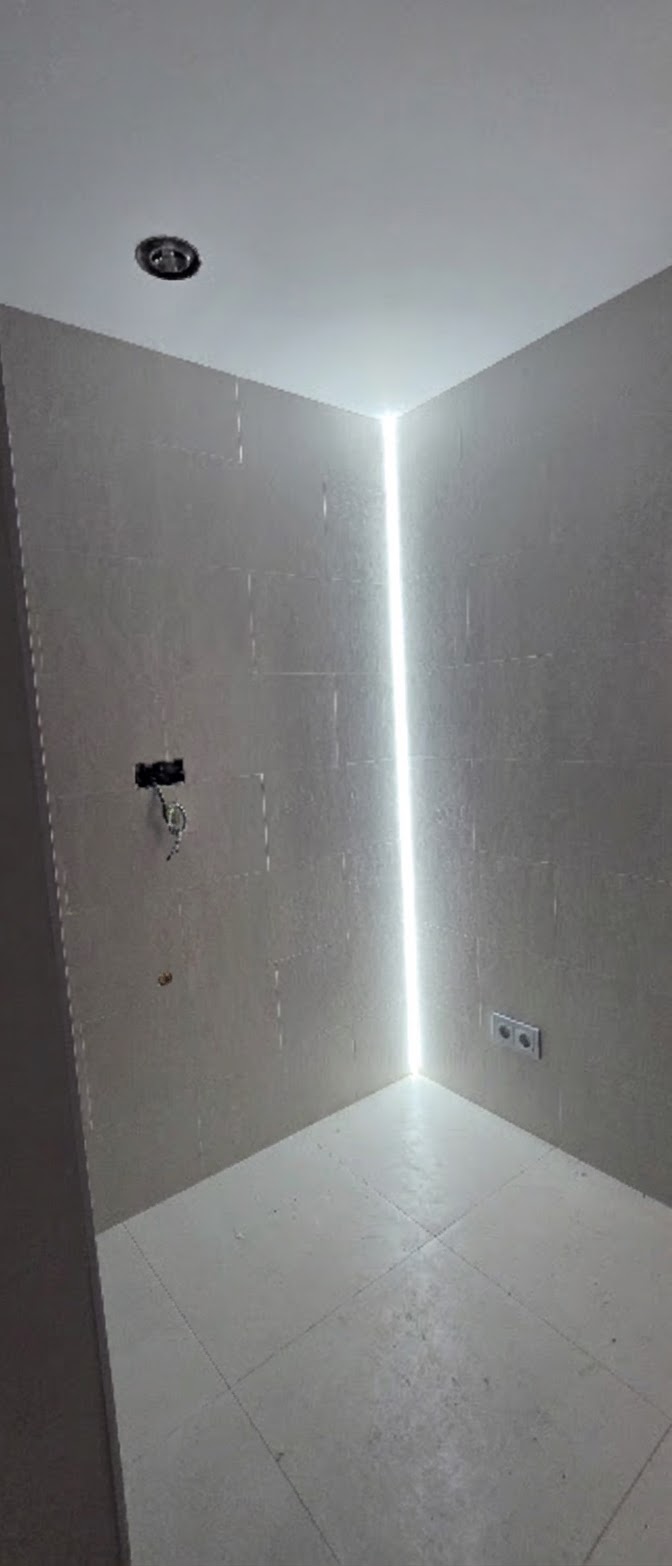 Tira de iluminación LED instalada en esquina de pared con caja de empalme eléctrico visible durante la reforma